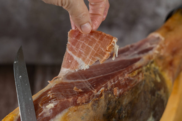 spanish acorn-fed iberian ham close-up open knife cut by the hands of a charcuterie woman - Fotografie, Obrázek