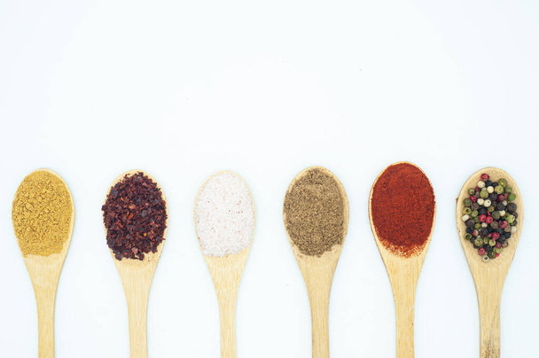 various spices in a wooden spoon on a white background - Фото, изображение
