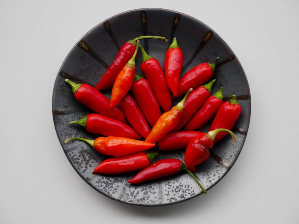 Aerial view of red hot chilis on black ceramic plate. - Фото, зображення