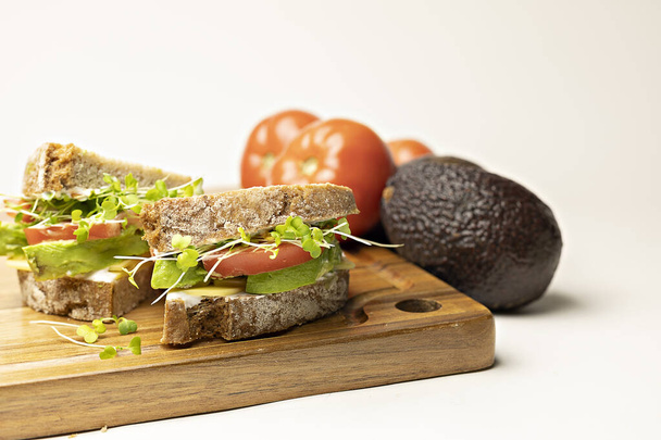 sándwich con salmón, aguacate, tomate y lechuga sobre fondo de madera blanca - Foto, Imagen