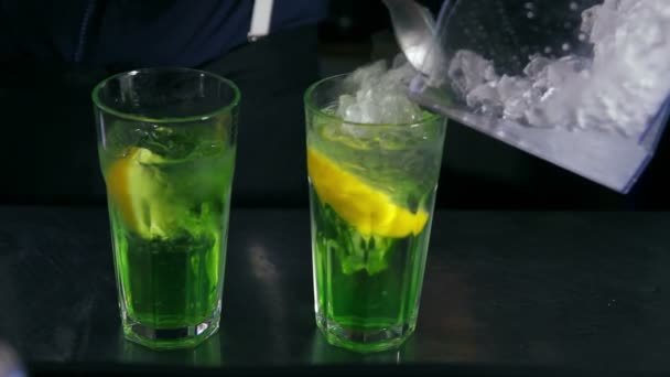 barman leje lodu i dekorowanie dwa koktajle z miętą - Materiał filmowy, wideo