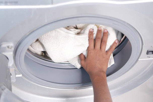 τοποθέτηση πετσετών και πανιών σε πλυντήριο ρούχων. - Φωτογραφία, εικόνα