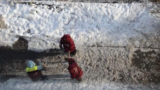 Vrouwelijke arbeiders breken ijs met koevoet op de weg - Video