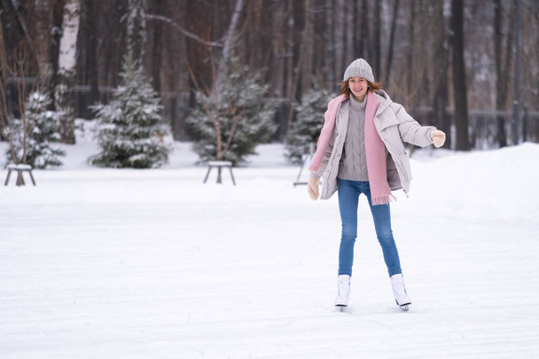 Дівчина катається на ковзанах у міському парку. Молода жінка активно проводить зимовий день на льоду. Зимові види спорту
 - Фото, зображення