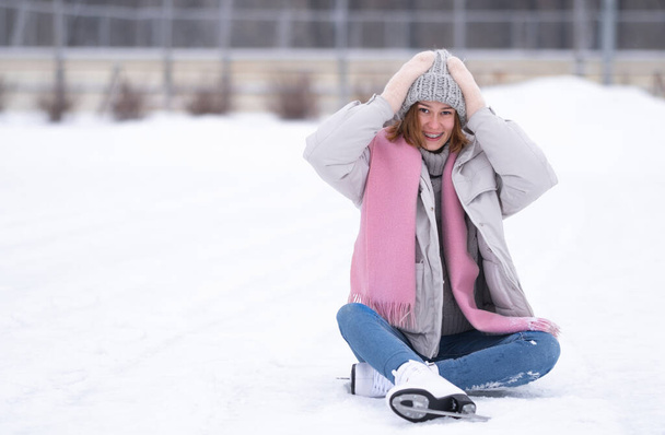 A girl is skating in a city park. A young woman actively spending a winter day on the ice. Winter sports - Photo, Image