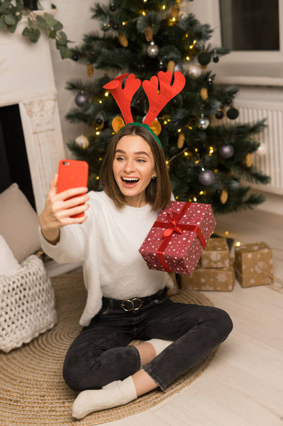 Közelkép fiatal lány telefon a szülők, és mutassa meg a piros karácsonyi ajándék - Fotó, kép