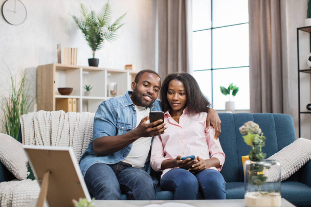Loving couple sitting on couch and using smartphones - Photo, Image