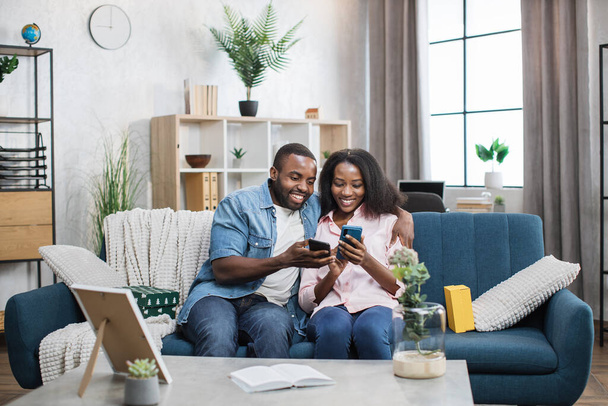 Happy couple relaxing on sofa with smartphones in hands - Foto, immagini