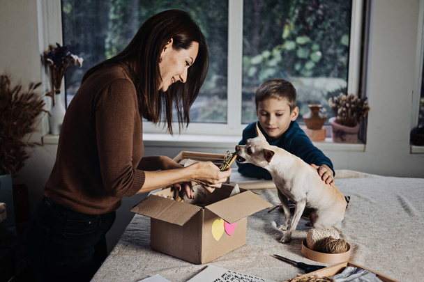 Happy family mom and kid putting bone in Pet Subscription Box for Dogs. Chihuahua dog and Subscription pet box with Organic Treats, Fun Toy, Bully Sticks, All-Natural Chews seasonal gear - Fotografie, Obrázek
