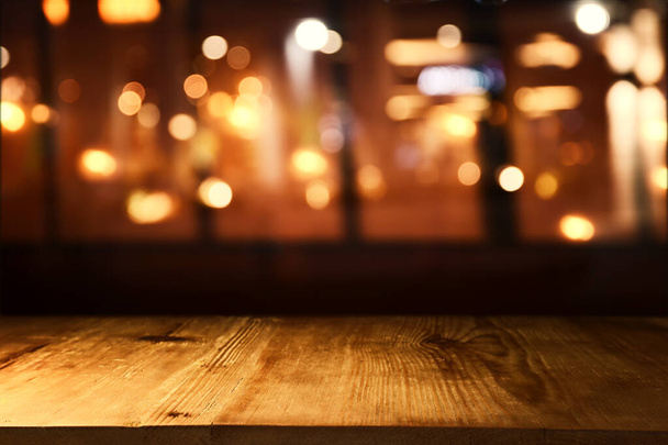 background Image of wooden table in front of abstract blurred restaurant lights - Photo, Image