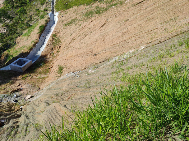 Постоянная защита склона травой методом гидросемени. Трава используется для стабилизации структуры склона и предотвращения эрозии склона. Эффективное и меньшее обслуживание.  - Фото, изображение