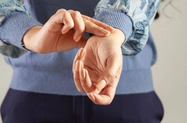 Female hand checking pulse on grey background - Foto, imagen