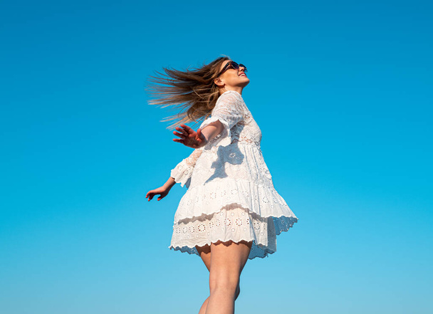 Movement girl in white dress on sky. Beautiful girl in stylish fashion clothes in summer. Fashion woman posing outdoors. Carefree women outside. - Zdjęcie, obraz