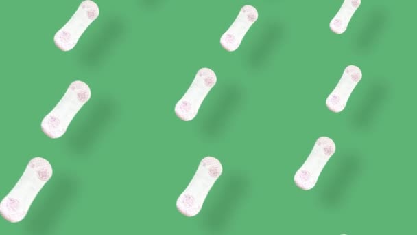 Kleurrijk patroon van dagelijkse damesmaandverband op groene achtergrond met schaduwen. Naadloos patroon met menstruatiepad. Bovenaanzicht. Realistische animatie. 4K video beweging - Video