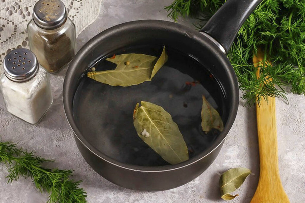 Pour in hot water, place a ladle on the stove and bring the brine to a boil. Turn off the heat, pour in the vinegar and cool in the cold for about 30-40 minutes. - Foto, imagen