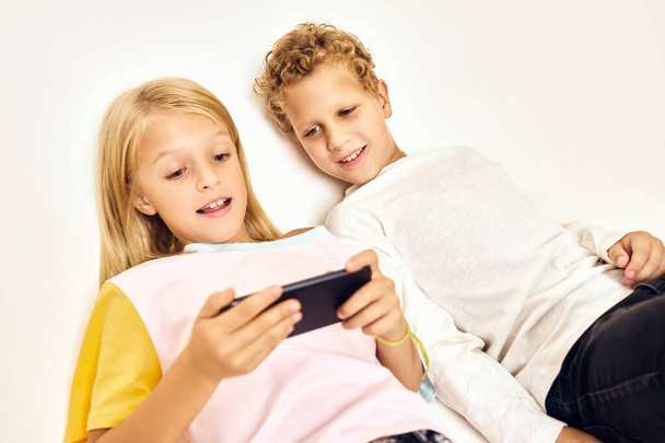 crianças pequenas com um telefone em suas mãos jogando jogos - Foto, Imagem