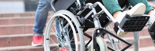 Άντρας τραβώντας ανάπηρος γυναίκα σε αναπηρική καρέκλα μέχρι βήματα closeup - Φωτογραφία, εικόνα