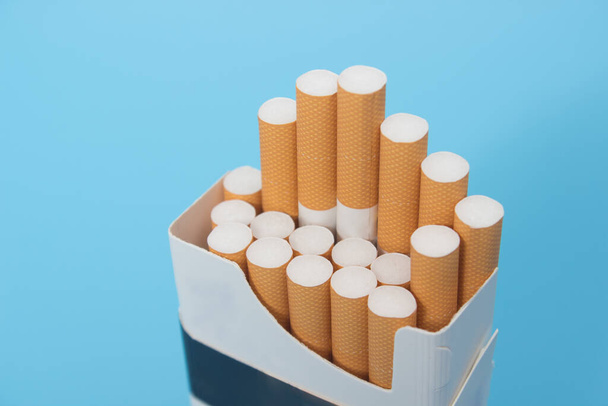 Closeup shot of cigarette pack over blue background - 写真・画像