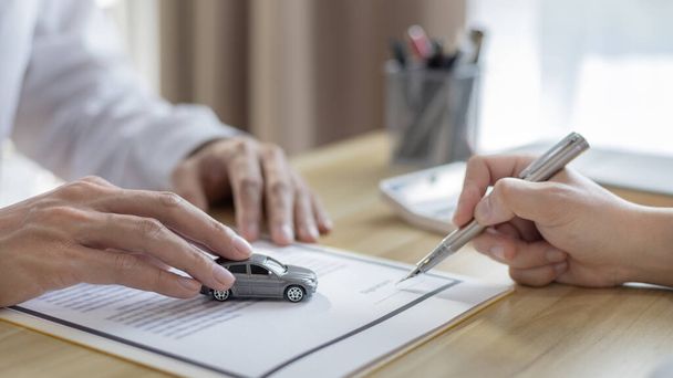 ディーラーまたはマネージャーは、保険で車の購入文書に署名した顧客に車を提供し、契約書に署名して合法的な車を購入する文書署名とクレジット承認コンセプト. - 写真・画像