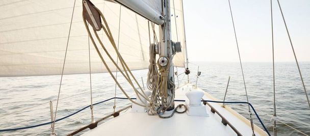 Λευκό γιοτ σε μια ανοιχτή θάλασσα σε μια σαφή ημέρα. Θέα από το κατάστρωμα προς την πλώρη, κατάρτι και πανιά, εξοπλισμός εξέδρας σε κοντινό πλάνο. Θερινό Ατλαντικό ιστιοπλοΐα κοντά στην Ισπανία και την Αφρική - Φωτογραφία, εικόνα