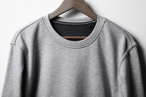 Grey jumper hanging on white wall - Photo, image