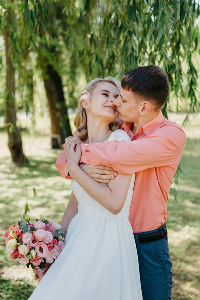 Bride and groom at wedding Day walking Outdoors on spring nature. Bridal couple, Happy Newlywed woman and man embracing in green park. Loving wedding couple outdoor. Wedding shot of bride and groom in - Fotografie, Obrázek