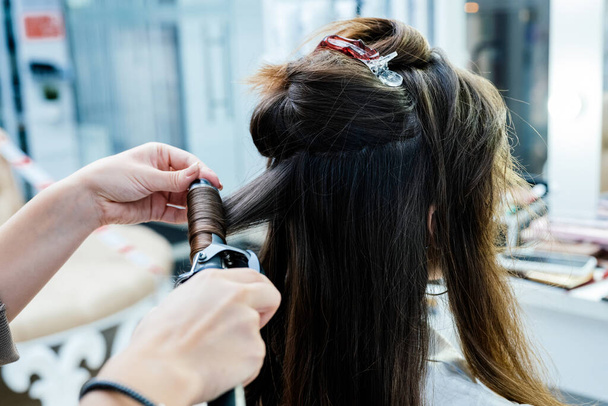 Głowa brunetka kobieta z kręconymi włosami do stylizacji włosów w salonie piękności. - Zdjęcie, obraz