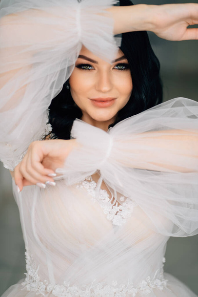 close-up. beautiful brunette bride in white dress with transparent puffy sleeves - Fotografie, Obrázek
