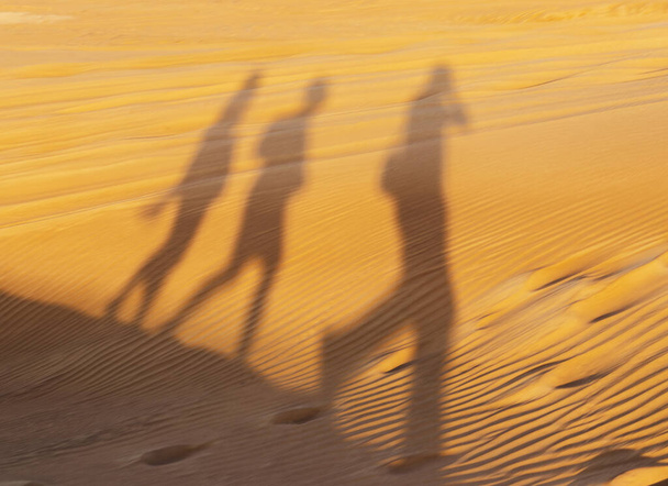 Kum tepesinde yürüyen insanların gölgeleri - Fotoğraf, Görsel