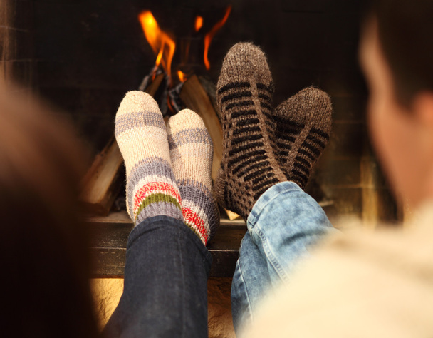Jambes d'un couple en chaussettes devant la cheminée à la saison d'hiver
 - Photo, image
