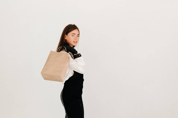 Jeune serveuse dans un sac en papier uniforme contenant de la nourriture à emporter, prête à la remettre à un client - Photo, image