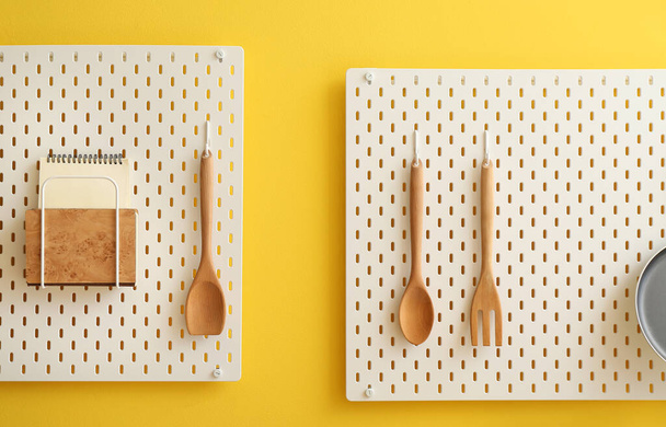 Tableaux de cheville avec cahiers et spatules suspendus au mur jaune - Photo, image