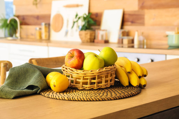Wicker basket with healthy fruits on table top in kitchen - Fotó, kép