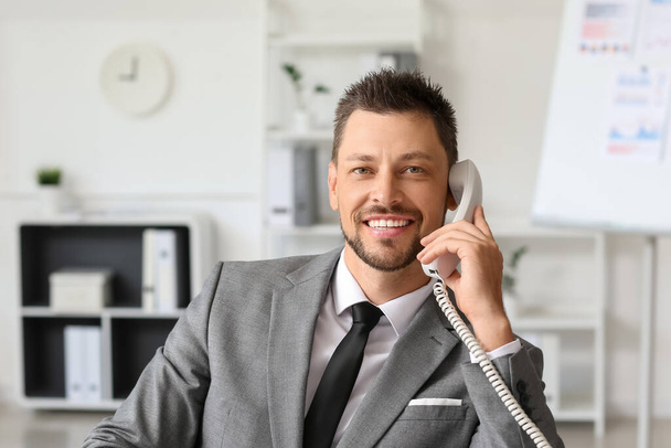 Smiling businessman talking by telephone at table in office - Foto, Imagem