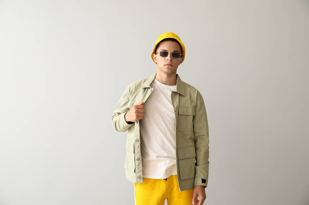 Young man in stylish bucket hat and jacket on light background - Foto, Imagem