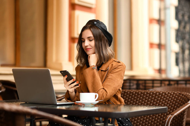 Jeune femme avec téléphone portable dans un café de rue
 - Photo, image