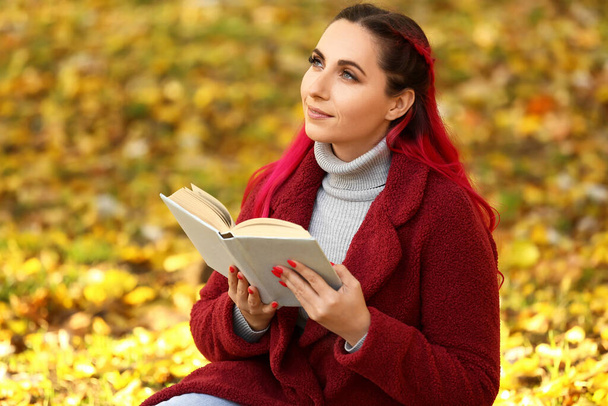 Dreaming beautiful woman with warm coat and book in autumn park - Foto, Imagem