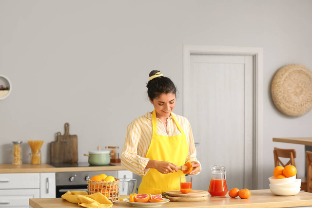 Mujer joven haciendo jugo fresco de cítricos en la cocina - Foto, imagen