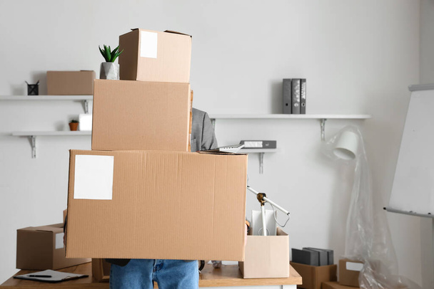 Man holding cardboard boxes with belongings in office on moving day - Фото, изображение