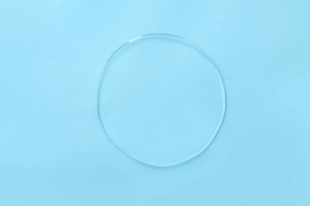 Vlek van vloeibare transparante gel op blauwe achtergrond - Foto, afbeelding