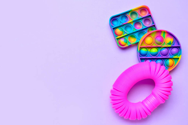colorato pop tubo e pop esso fidget giocattoli su sfondo viola - Foto, immagini