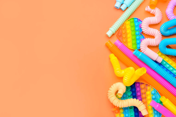 Colorful Pop Tubes and Pop it fidget toys on orange background - Fotó, kép