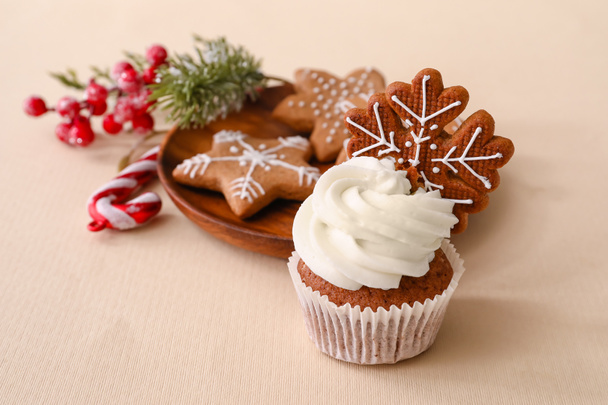 Tasty Christmas cupcake with gingerbread cookies on beige background - Foto, Bild