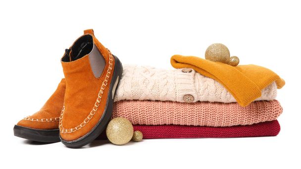 Stack of knitted sweaters, shoes, hat and Christmas balls on white background - Фото, изображение