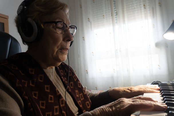 Kaukaska starsza kobieta uczy się muzyki i gra na klawiszach muzycznych - Zdjęcie, obraz