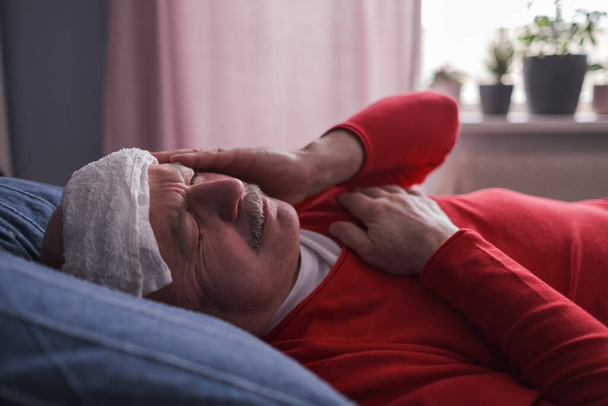 Un maschio malato che dorme con un asciugamano bagnato sulla fronte per ridurre la febbre alta
 - Foto, immagini
