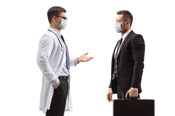 Male doctor and businessman with medical face masks standing and talking isolated on white background - Fotografie, Obrázek