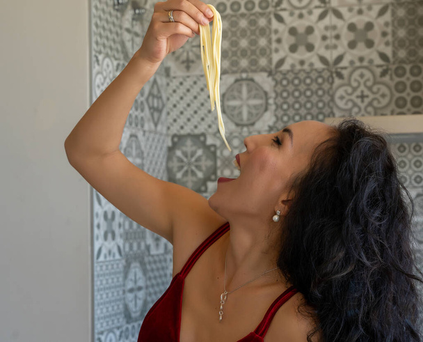 woman putting several pieces of spaghetti in her mouth, head thrown back, close-up horizontal picture - Photo, Image