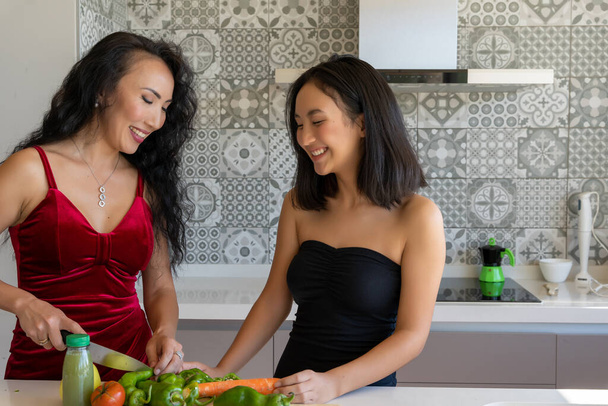 İki kadın mutfakta dikilmiş, resmi giyinmiş sebzeleri doğruyor. - Fotoğraf, Görsel