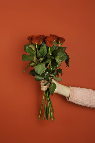 Krásná kytice rudých růží v ruce ženy izolované na bílém pozadí. Módní plakát na Valentýna, Mezinárodní den žen nebo Den matek. - Fotografie, Obrázek